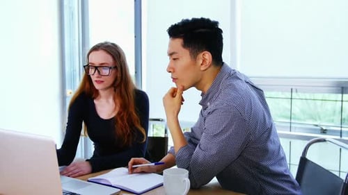 Colleagues Collaborating at a Laptop in Modern Office