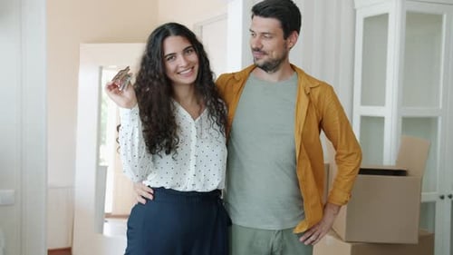 Portrait of Man and Woman Standing Indoors Holding House Key Smiling Hugging