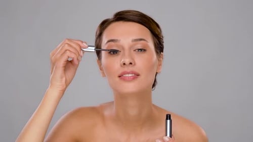 Porträt einer schönen jungen Frau beim Auftragen von Mascara