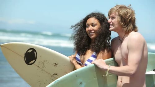 Portrait of couple at beach with surfboards