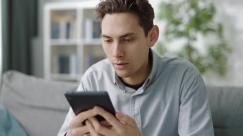 Man Browsing Tablet on Couch Indoors
