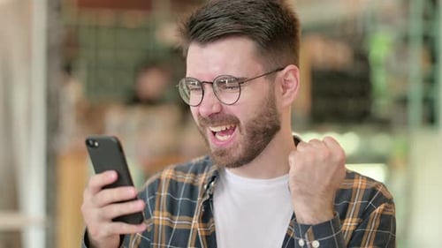 Man Exclaims Success While Holding Smartphone