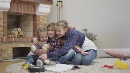Three Happy Children Embracing By Fireplace