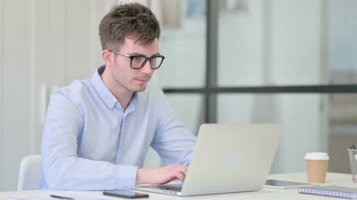 Young Man Working on Laptop in Office