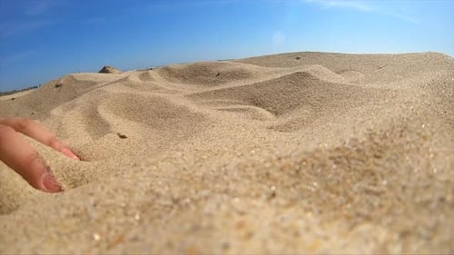 Hand playing with sand at a beach