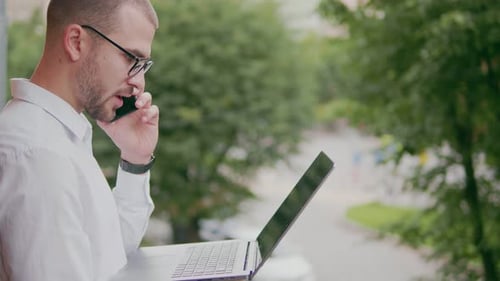 Man Working with Phone and Laptop Outdoors