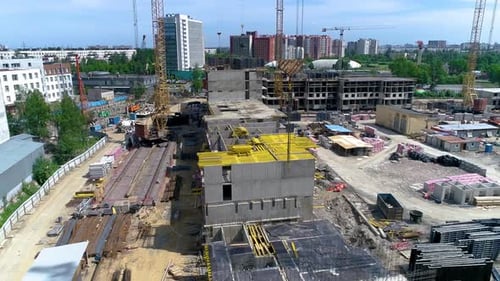 Ansicht einer Baustelle aus der Vogelperspektive. Gelber Kranausleger im Vordergrund