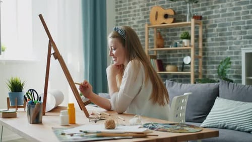 Woman Painting on Easel at Table in Home