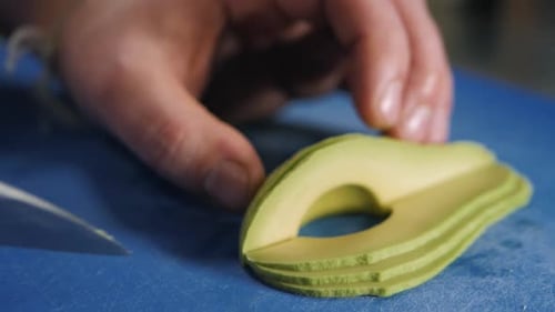 Close Up of Chef Male Hands Cooking with Avocado at Table Slice Knife Cut Macro
