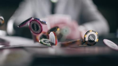 Casino Chips and Playing Cards are Falling Against the Background of a Player with Cards in Slow