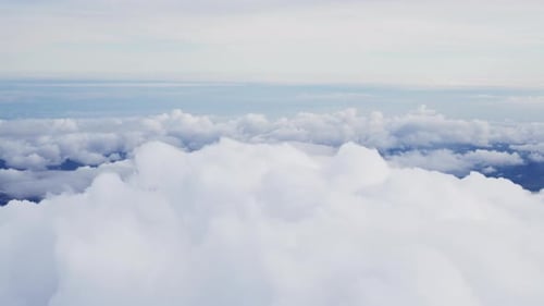View Through Plane Window on a Beautiful Blue Sky and Sea of Clouds