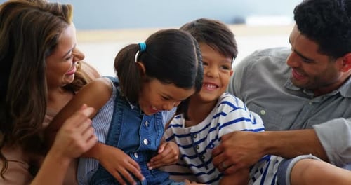 Happy Family Laughing Together on Couch at Home
