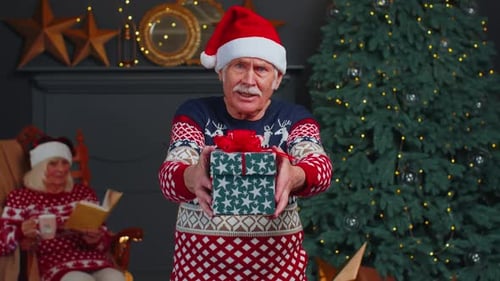 Senior Man Offering Christmas Gift to Camera