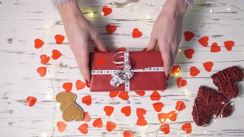 Female Hands Put a Gift Box on the Desk, Top View Down.