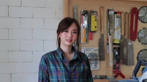 Worker young Asian woman carpenter crossed arm in wood workshop, small business