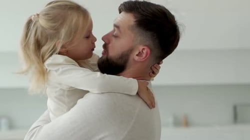 Loving Father Holding and Kissing Young Daughter