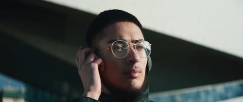 Young Adult Listens to Music Outdoors with Headphones