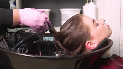 Young Woman Rinsing Purple Hair Dye at Salon