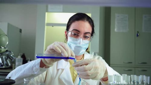 Woman Scientist Pours Blue Liquid in Laboratory
