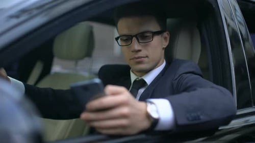 Young Adult Using Smartphone in Car Smiling