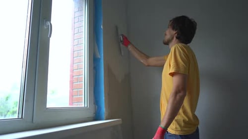Man Plastering Wall with Trowel Indoors