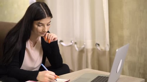 Woman Works on Laptop at Table at Home