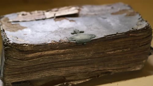 A very old book with a broken lock on it. CLOSE UP and ZOOM OUT