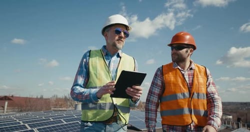 Ingeniero y técnico discutiendo entre paneles solares