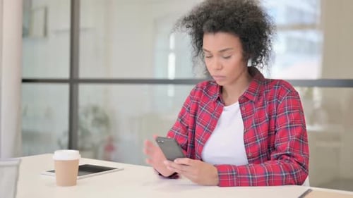 Young Adult Using Mobile Phone at Desk Indoors