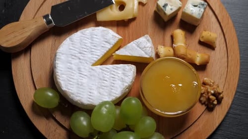 Overhead shot of cheese board with grapes and honey