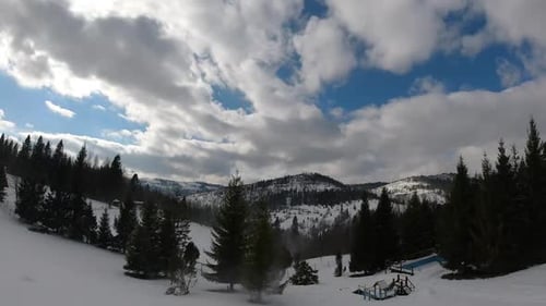 Nuages en timelapse flottant dans le ciel. Collines et montagnes enneigées. Heure d'hiver.