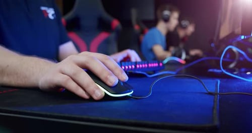 Close-up on the Hands of the Gamer Playing in the Video Game Using Mouse Background with Cool Neon