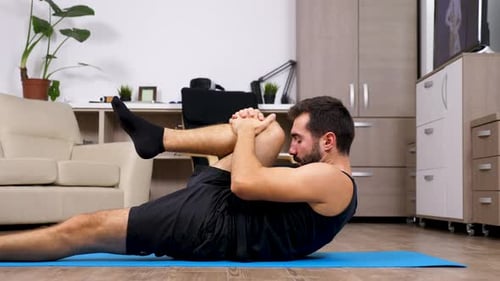 Man Doing Leg Stretches on Yoga Mat Indoors