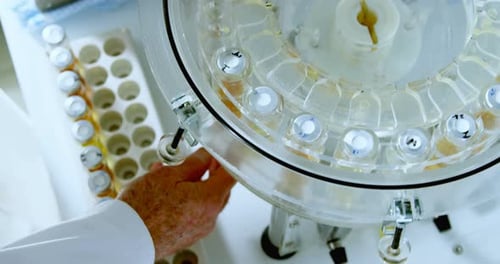 Scientist Loads Vials Into Centrifuge for Lab Research