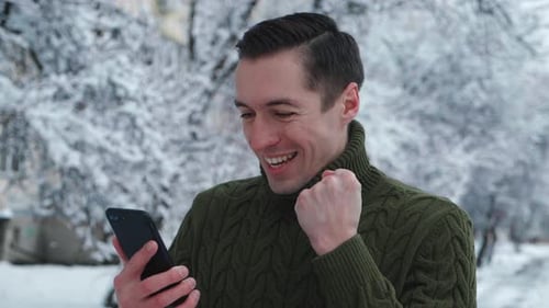 Excited man reacts to good news on phone