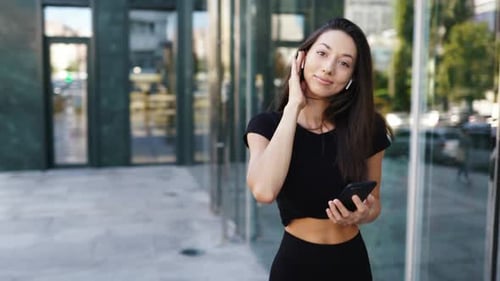 Portrait of a Young Brunette Woman with Headphones While Walking