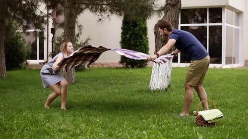 Couple Laying Blanket in Yard for Picnic