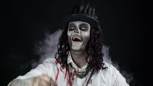 Frightening Smiling Man in Skeleton Halloween Costume in Bloody Shirt Looking and Pointing at Camera