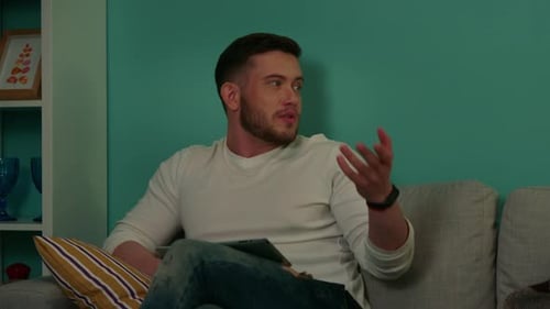 Man Talking and Gesturing Indoors on Couch