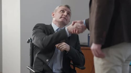 Porträt eines gelähmten grauhaarigen älteren Mannes beim Händeschütteln eines unkenntlichen Geschäftspartners