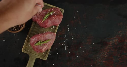 A mão masculina derrama sal em medalhões de carne bovina