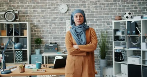 Porträt einer ehrgeizigen Frau gemischter Rassen im Hijab, die im Büro mit verschränkten Armen