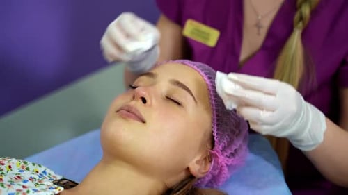 Cosmetologist cleans the skin of a woman's face before a cosmetic procedure
