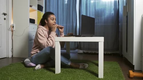 Girl Eats Food While Using Laptop Indoors