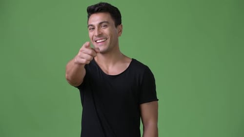 Young Handsome Hispanic Man Against Green Background