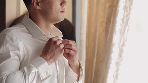Man Buttons Dress Shirt Near Window
