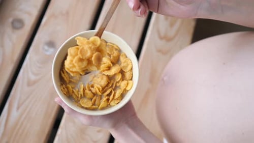 Top View Of Pregnant Woman Eating Cereals For Breakfast.