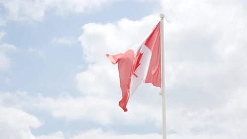 Canadian Flag Waving Proudly Against Blue Sky