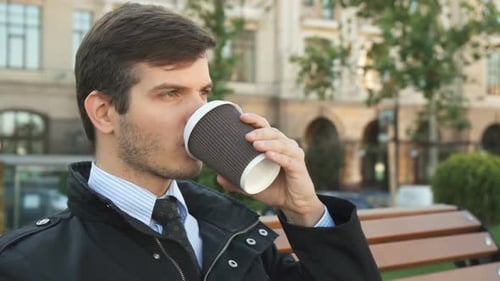 Young Adult Man Drinking Coffee on Park Bench