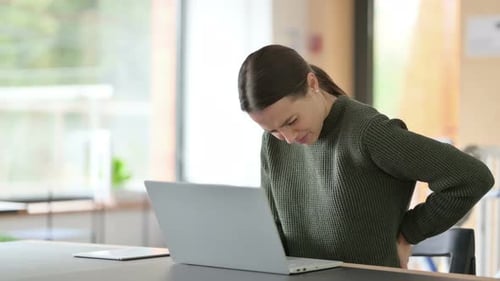 Young Woman Experiencing Back Pain at Office Desk